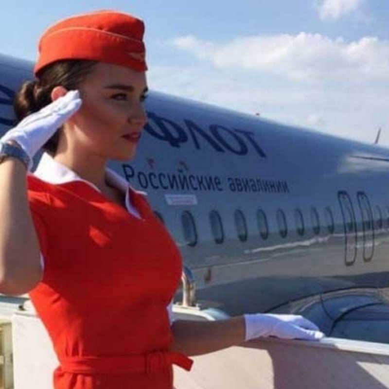 Открытка стюардесса в красном отдает честь чудесного полета Gute Reise 